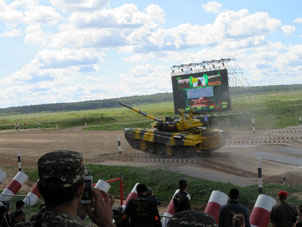 El tanque pasa cerca del monitor donde se muestra que es el líder de la carrera.